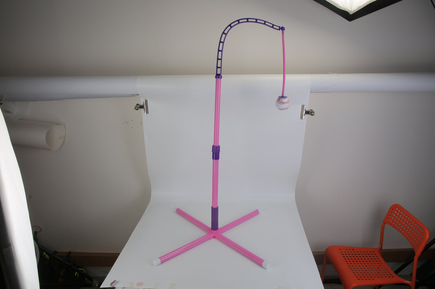 Pink and purple stand on a white surface with a chair and lamp in the background
