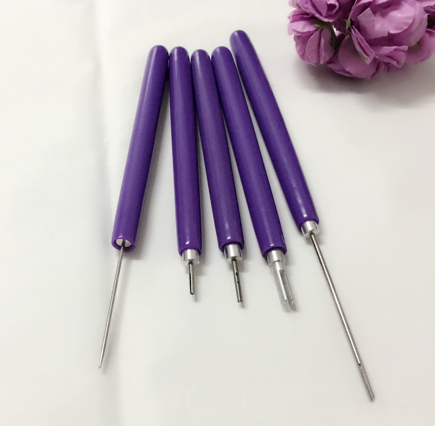 Set of purple-handled tools with metallic ends on a white background