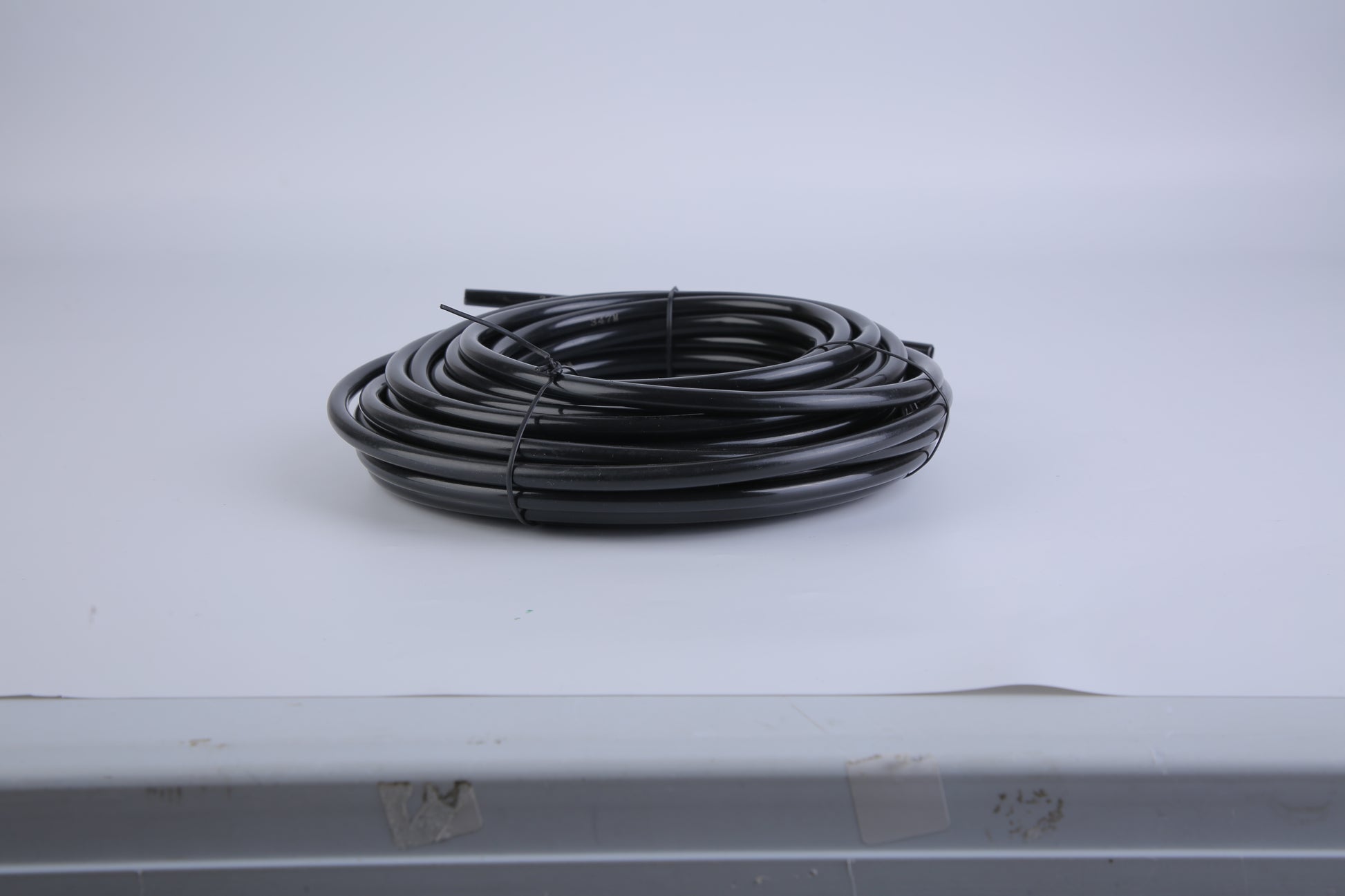 Coiled black hose on a white surface