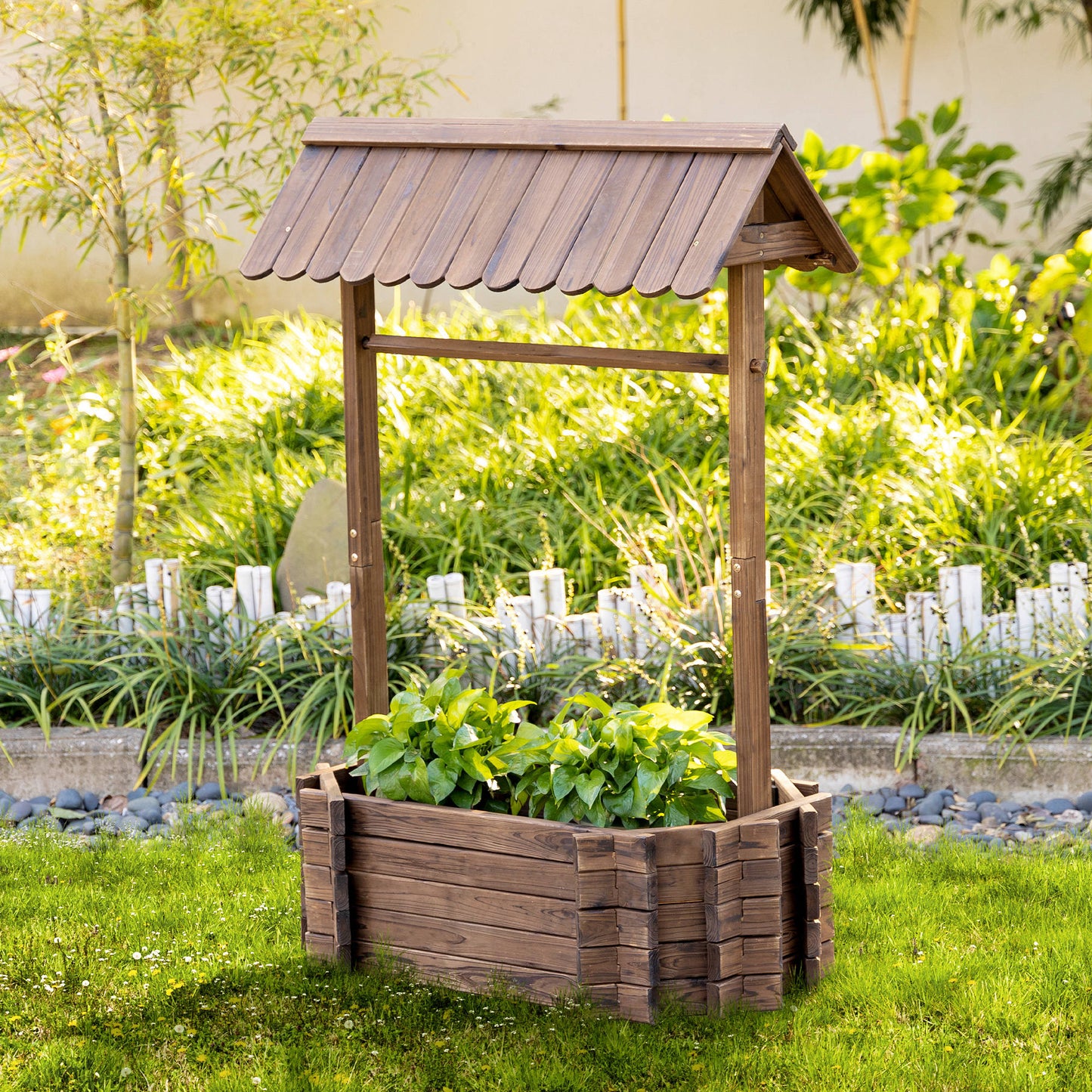 Wooden wishing well planter with plants in a garden setting